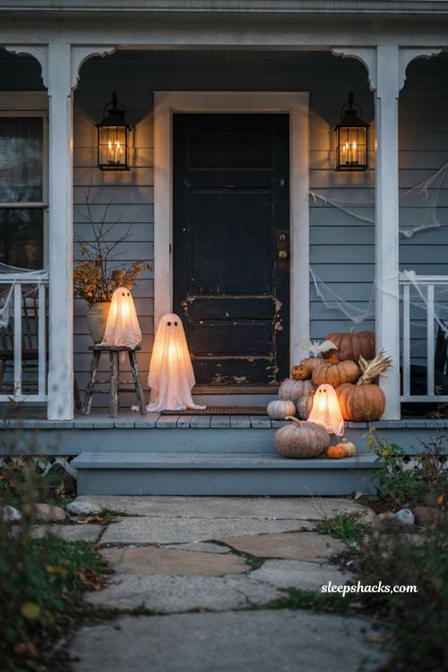 Illuminated ghost figurines Halloween porch with pumpkins and cozy vintage decor