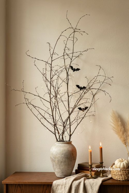 Leafless branch Halloween decor with twig tree bats string lights and neutral fall styling