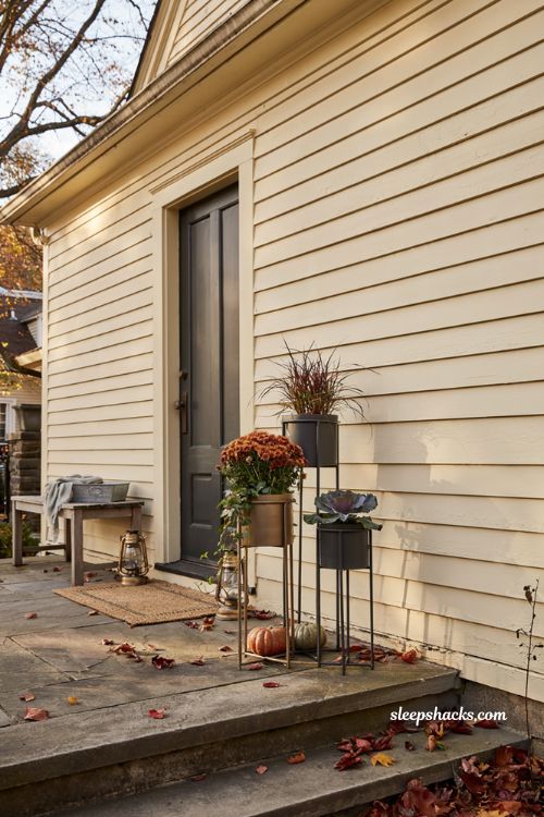 Metal fall planters on stands with mums and foliage for front porch decor