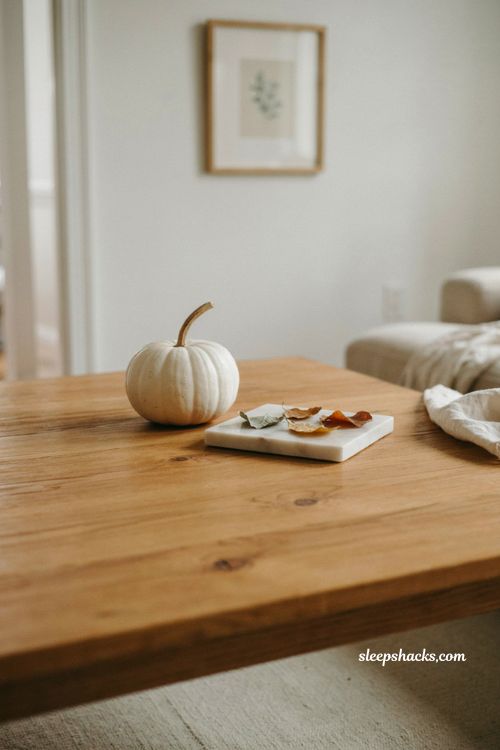 Minimal fall coffee table decor with a white pumpkin marble tray and loose autumn leaves 