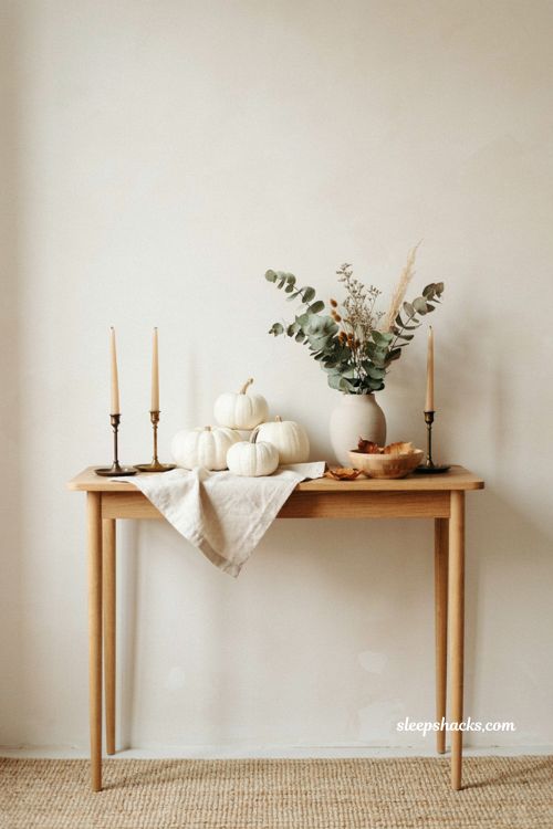 Minimalist Halloween entryway with white pumpkins fall foliage and candles 