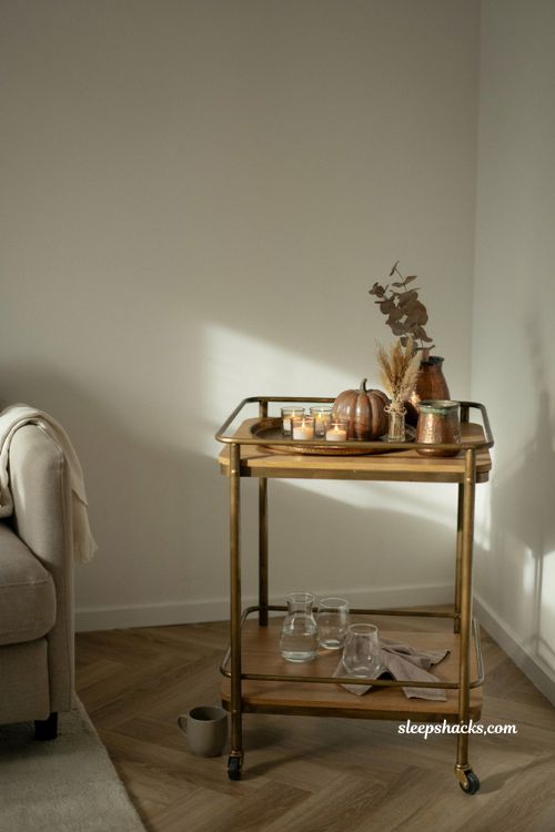Minimalist fall decor bar cart vignette with candles brass accents and dried grasses 