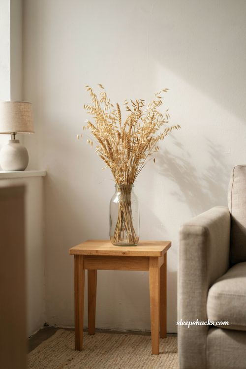 Minimalist fall decor with dried wheat in glass vase on neutral side table 