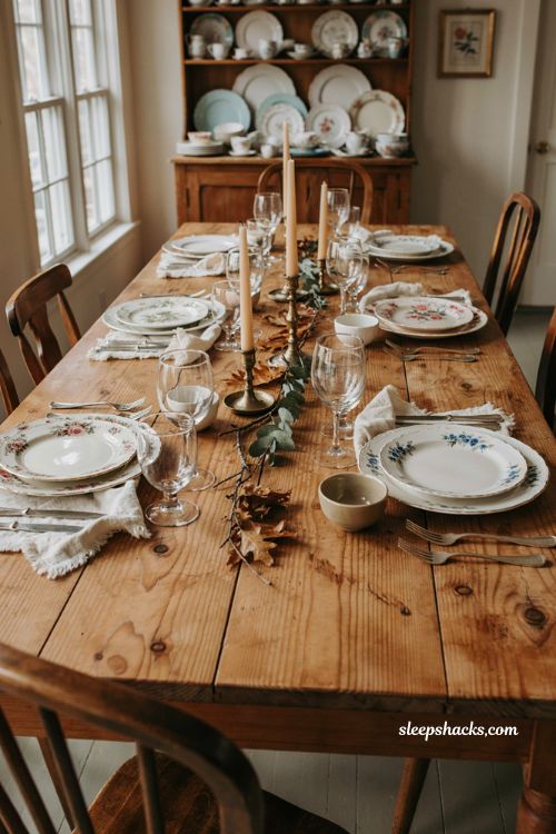 Mismatched china Thanksgiving table with vintage floral plates cream dishes gold flatware and warm neutral table decor 