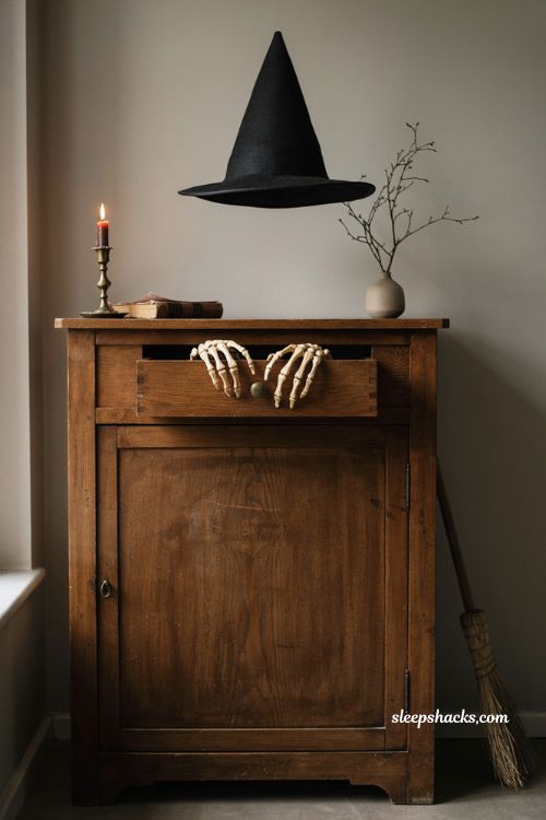 Modern Halloween decor with skeleton hands antique cabinet witch hat and broom