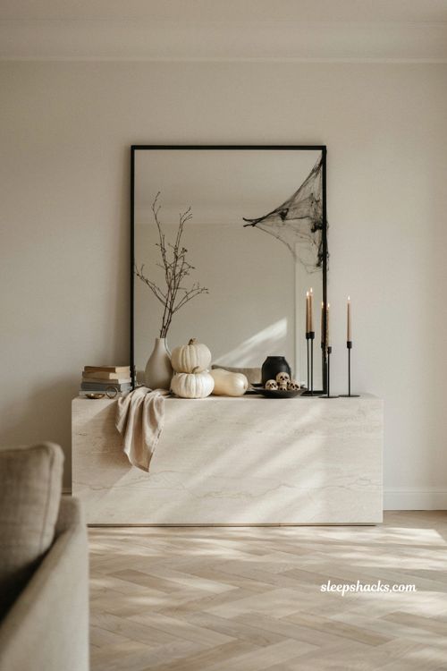 Modern black and white Halloween decor with white pumpkins black candlesticks and spiderwebs