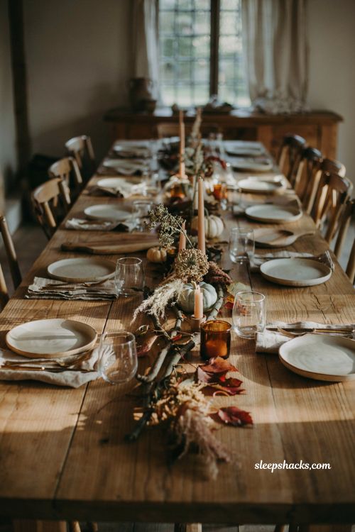 Modern fall decor with branches pumpkins and candles as a table centerpiece 