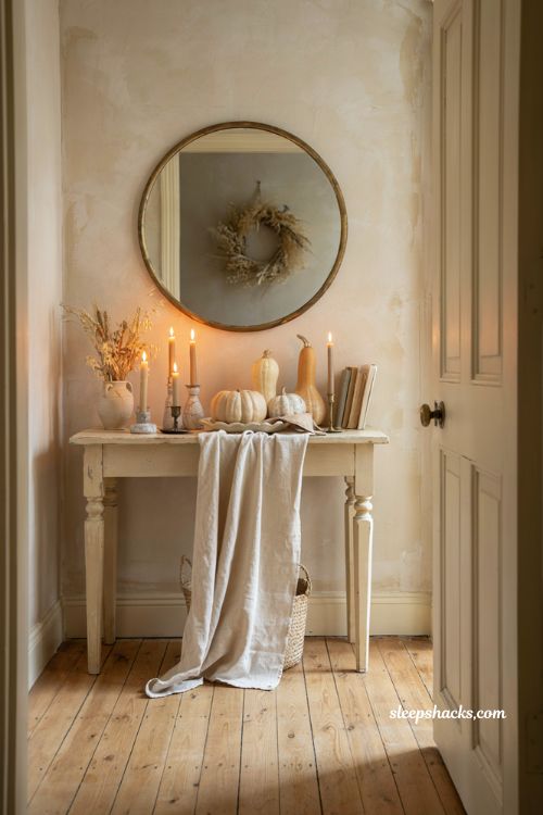 Monochromatic fall entryway table decor with cream pumpkins candles and neutral accents