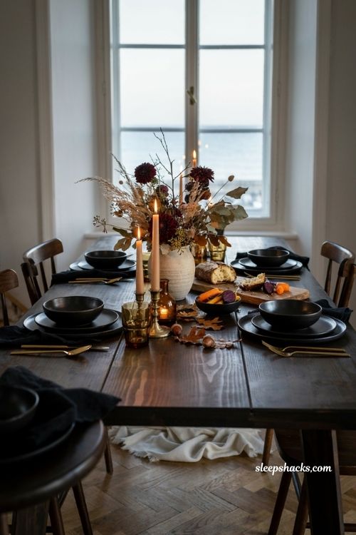 Moody fall dining table decor with dark florals black tableware and gold accents 