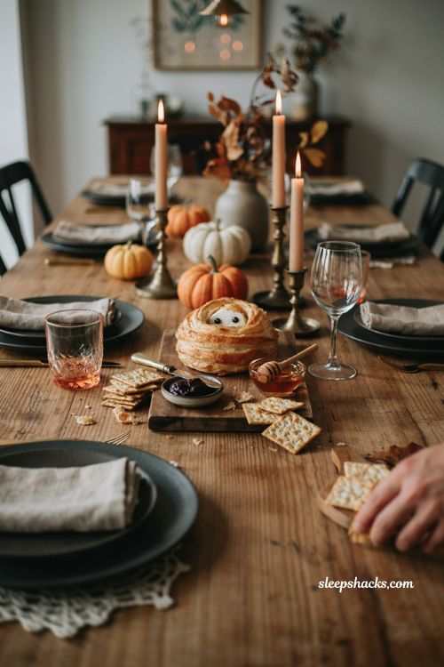 Mummy brie appetizer display with crackers and fig jam for a Halloween house party