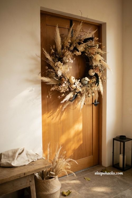 Neutral halloween decor with dried flower wreath feathers and muted pumpkins