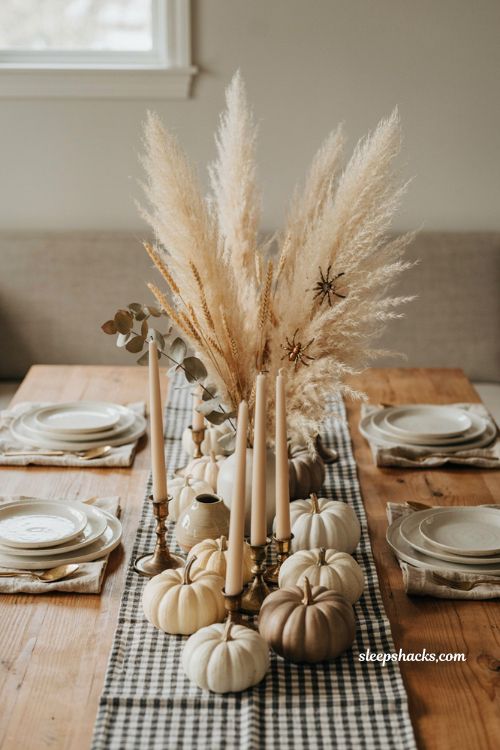 Neutral pumpkins pampas grass and chunky candlesticks for sophisticated Halloween table decor 