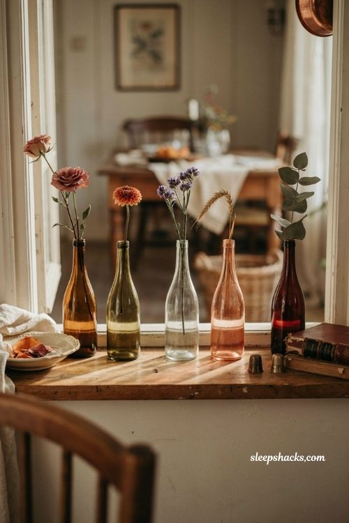 Old wine bottle bud vases with single autumn flowers for vintage fall decor