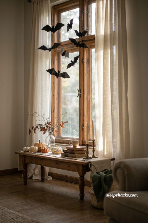 Origami paper bats hanging in a window for charming DIY Halloween decor