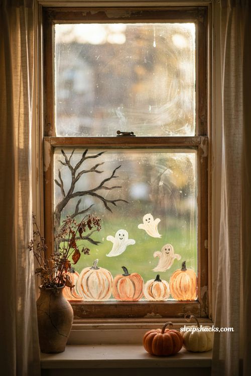 Painted Halloween window scene with pumpkins ghosts haunted tree and cozy autumn decor