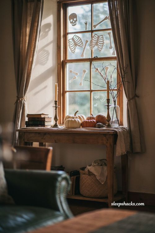 Paper skeleton cutouts scattered across a window for DIY Halloween decor
