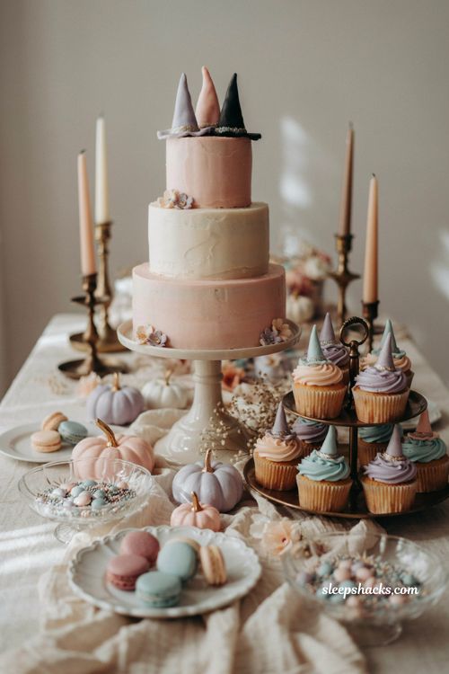 Pastel Halloween dessert table with mini witch hat cake toppers and cupcakes