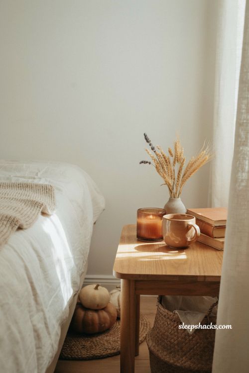 Pumpkin latte glass jar candle styling in a cozy autumn bedroom with warm neutral decor