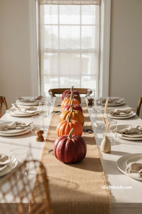 Red orange and peach ombré pumpkins on a white table with burlap runner for Halloween centerpiece decor