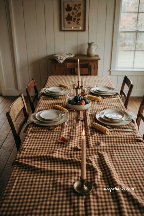 Rustic checked Thanksgiving tablecloth with brown gingham stoneware plates mini gourds brass candles and cozy farmhouse decor 