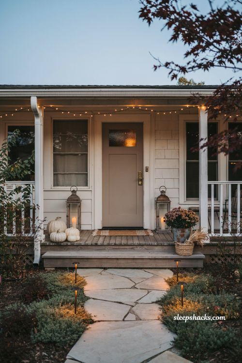 Simple fall front porch ideas with warm lantern lighting string lights and cozy autumn entry 