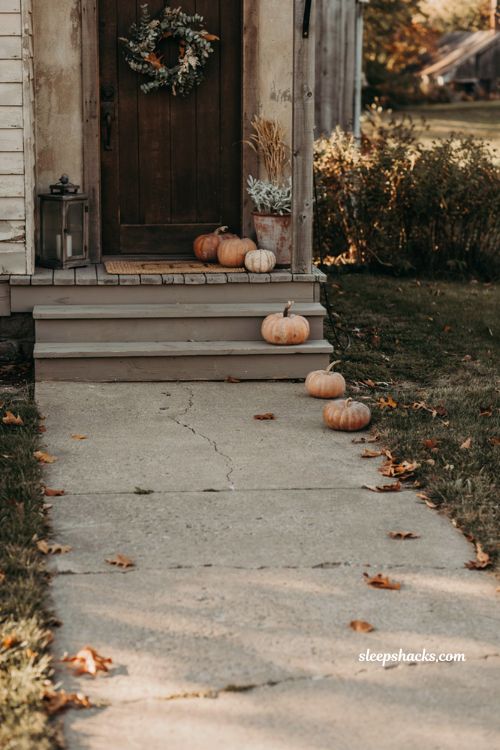 Simple small front porch fall decor with pumpkins along the walkway
