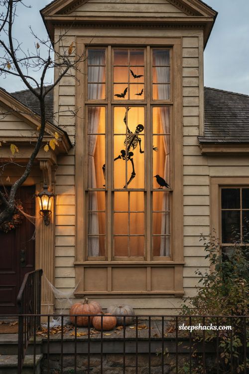 Skeleton window scene with climbing silhouette and flying bats for Halloween 