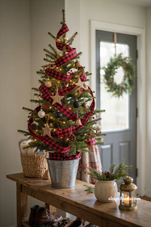 Small buffalo plaid Christmas tree with rustic farmhouse ornaments in an entryway