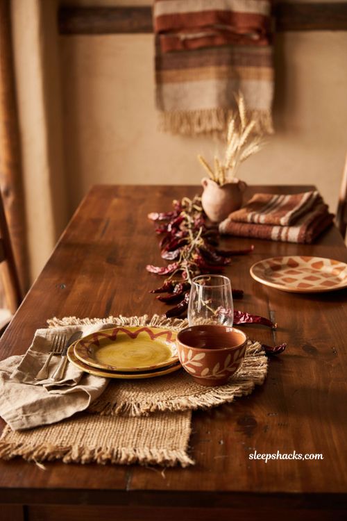 Southwestern Thanksgiving table setting with hand painted pottery woven placemats dried chiles and warm autumn colors 