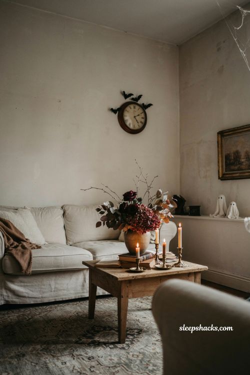 Subtle Halloween living room decor with bat decals, ghost figures, candles, and moody florals 