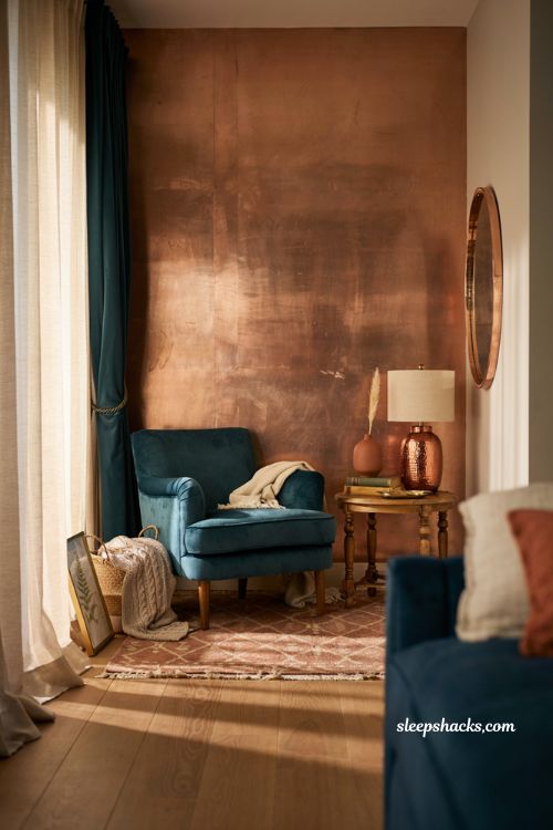 Teal and copper bedroom with metallic copper accent wall and velvet chair