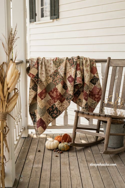 Vintage fall porch decor with faded quilt draped over porch railing