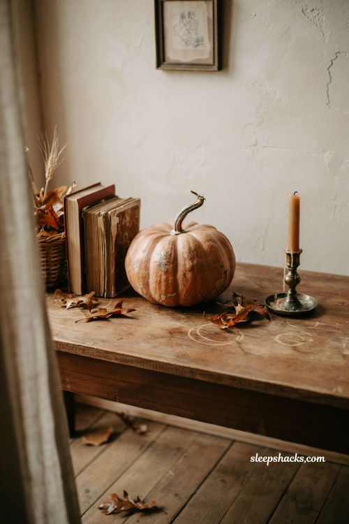 Vintage pumpkin vignette with antique books candles and dried leaves
