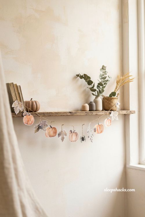 Watercolor Halloween ornament garland with pumpkins and spiders on a rustic shelf 
