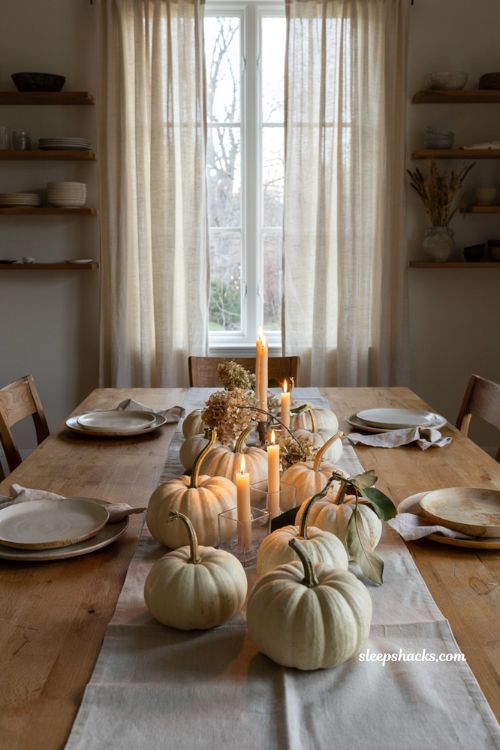 White pumpkin centerpiece with glowing votive candles for a cozy fall dinner table 