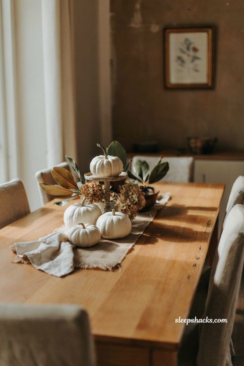 White pumpkin centerpiece with magnolia leaves and dried hydrangeas for an elegant fall table 