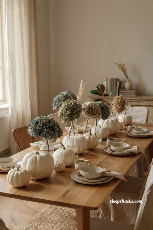 White pumpkin centerpiece with small glass vases and soft hydrangea blooms for fall 