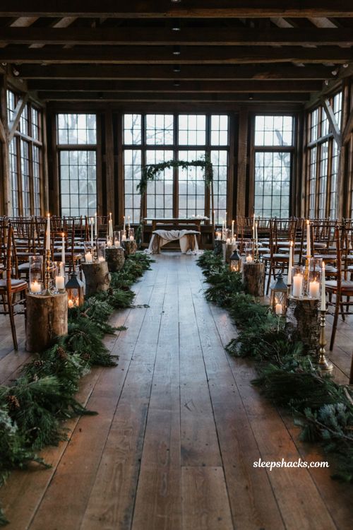 Winter wedding aisle ideas with candles greenery and rustic wood accents