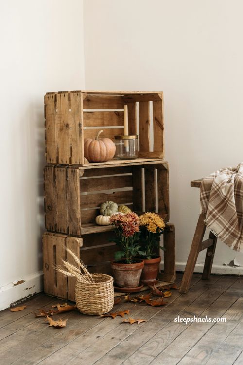 Wooden crate fall porch vignette with mini pumpkins mums candles dried wheat and rustic autumn decor 