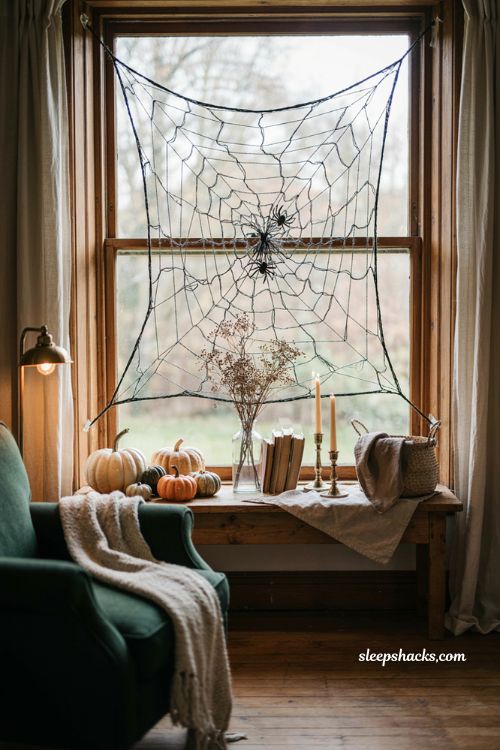 Yarn spider web stretched across a window for cozy DIY Halloween decor