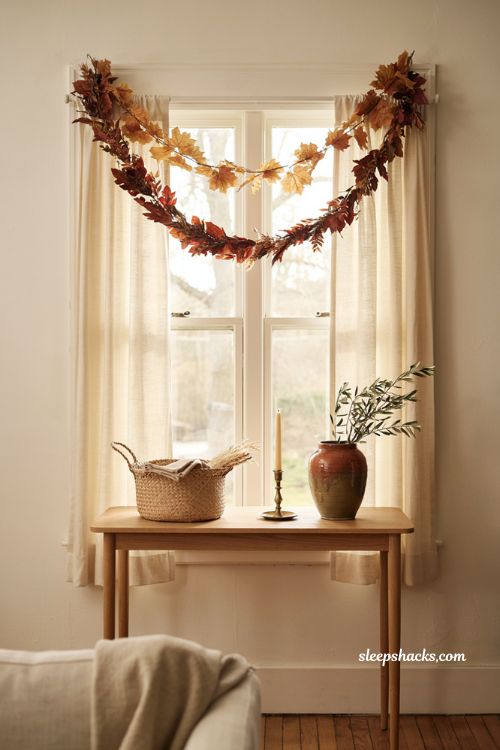 layered fall garlands above windows with warm maple rust and cozy living room decor