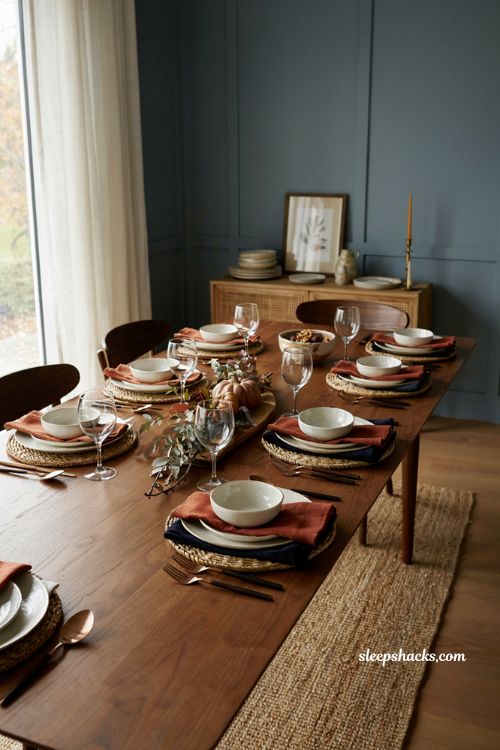 navy and rust Thanksgiving table with velvet napkins rattan chargers and fall decor