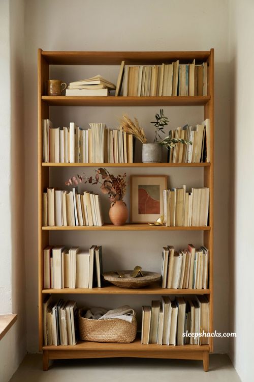 neutral bookcase with turned around books dried stems and warm fall decor