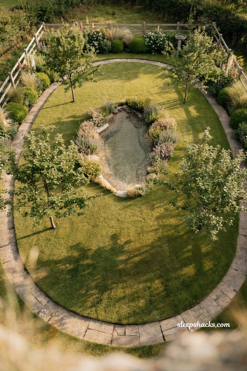 small natural pool with oval lawn border fruit trees and meadow garden design