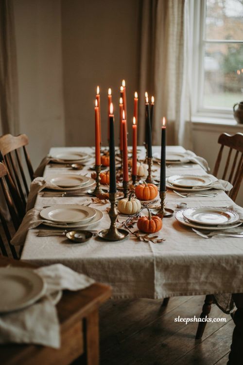 ```text Orange and black taper candles arranged in alternating colors along a cozy Halloween dinner table, vintage brass and dark ceramic candlesticks, plain white linen tablecloth, cream dinnerware, aged silverware, folded linen napkins, dried autumn branches, miniature pumpkins, warm amber candlelight, soft natural window light, elegant cottage dining room, sophisticated Halloween table decor, nostalgic autumn atmosphere, versatile seasonal styling, photorealistic editorial interior photography, Pinterest-worthy ``` 