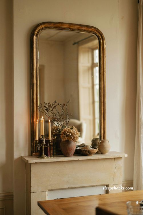 vintage mirror above a fall mantel with brass candelabra dried hydrangeas and warm decor