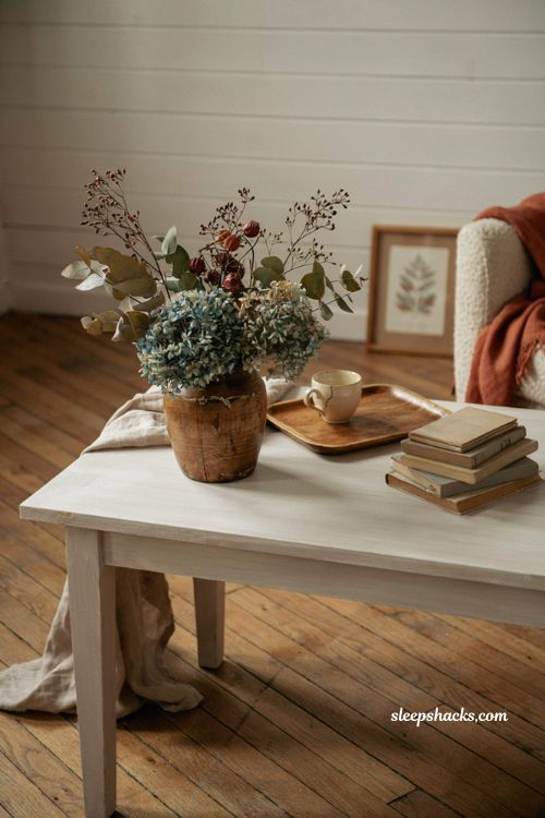 vintage wood vessel with hydrangeas berries and eucalyptus on a white coffee table