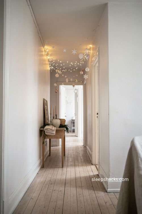 All white winter hallway with warm Christmas lights and hanging snowflakes 