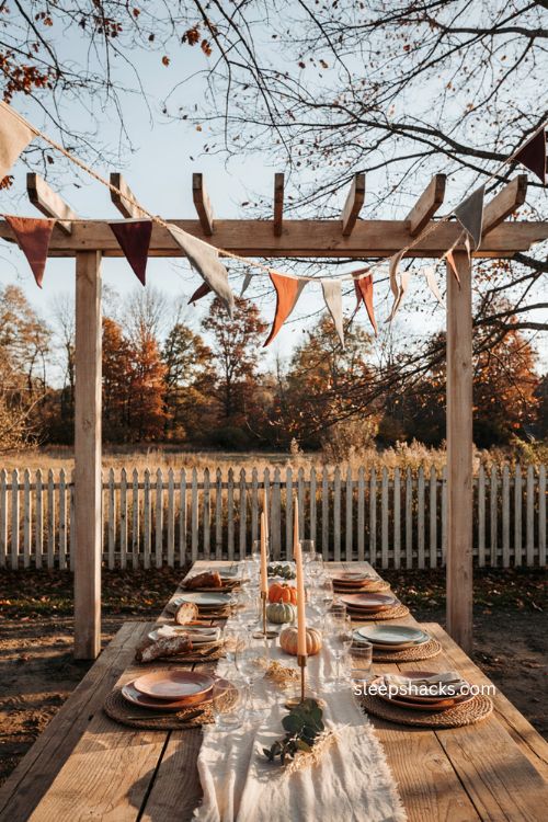 Autumn triangle bunting in burgundy sage and brown over a cozy outdoor Thanksgiving table
