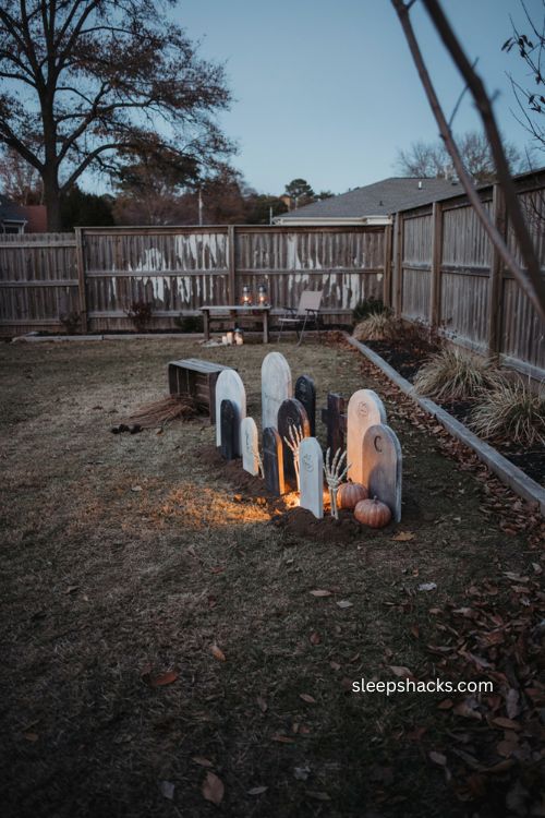 Backyard Halloween graveyard scene with diy tombstones and skeleton hands 